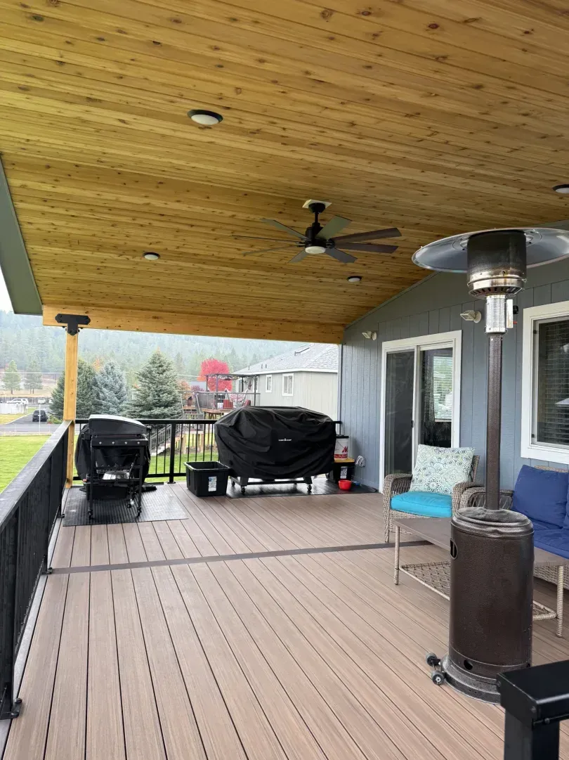 Covered deck with a cedar plank ceiling, ceiling fan, patio heater and two-tone composite decking