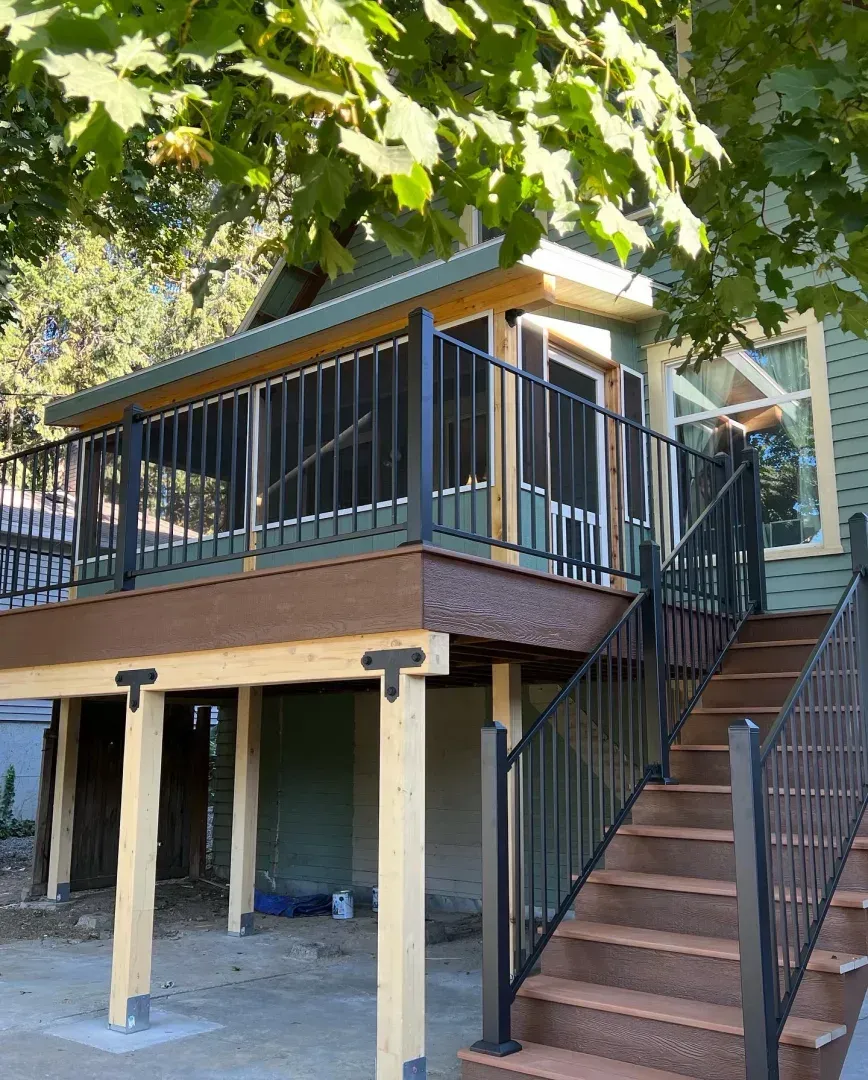 Elevated deck with black aluminum railing, exposed cedar post framing and matching stair railing, built by Dynamic Decks