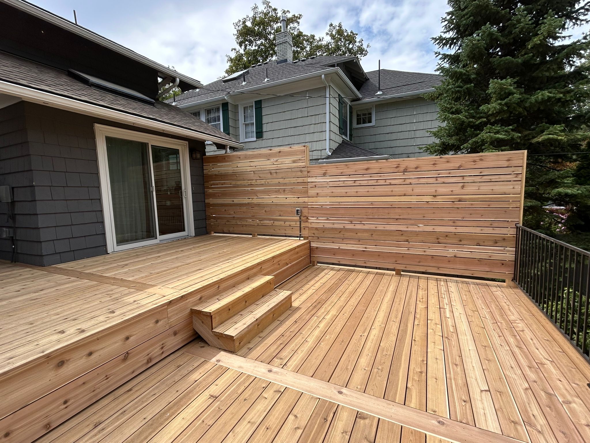 New cedar wood deck with built-in steps and a horizontal cedar privacy screen
