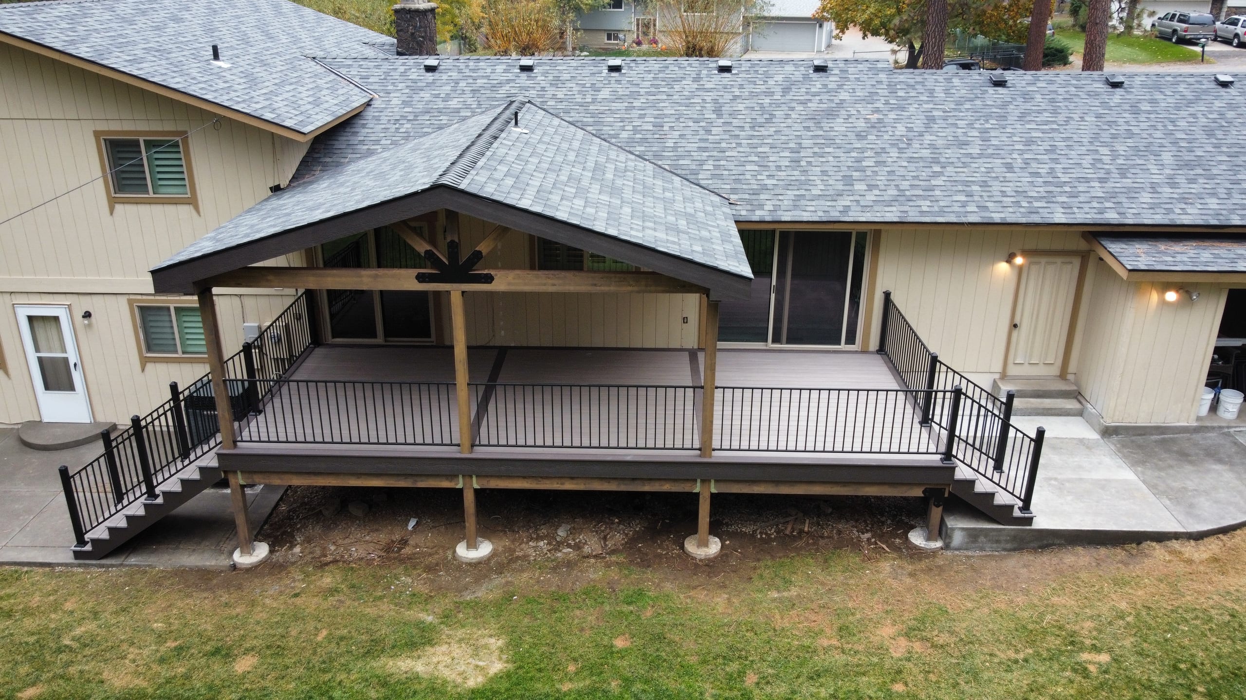 Aerial view of a raised deck with gabled cover, black railing and two stairways