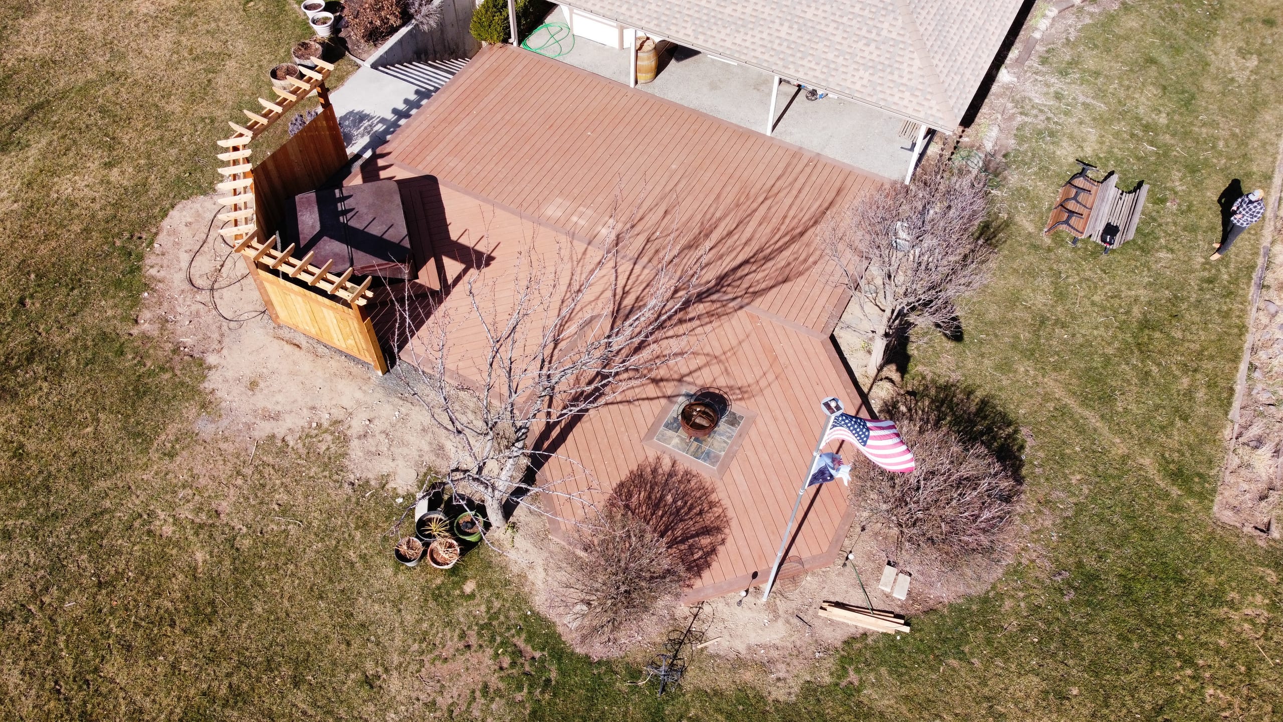 Aerial of reddish composite deck with cedar corner screen, fire pit and flagpole beside house