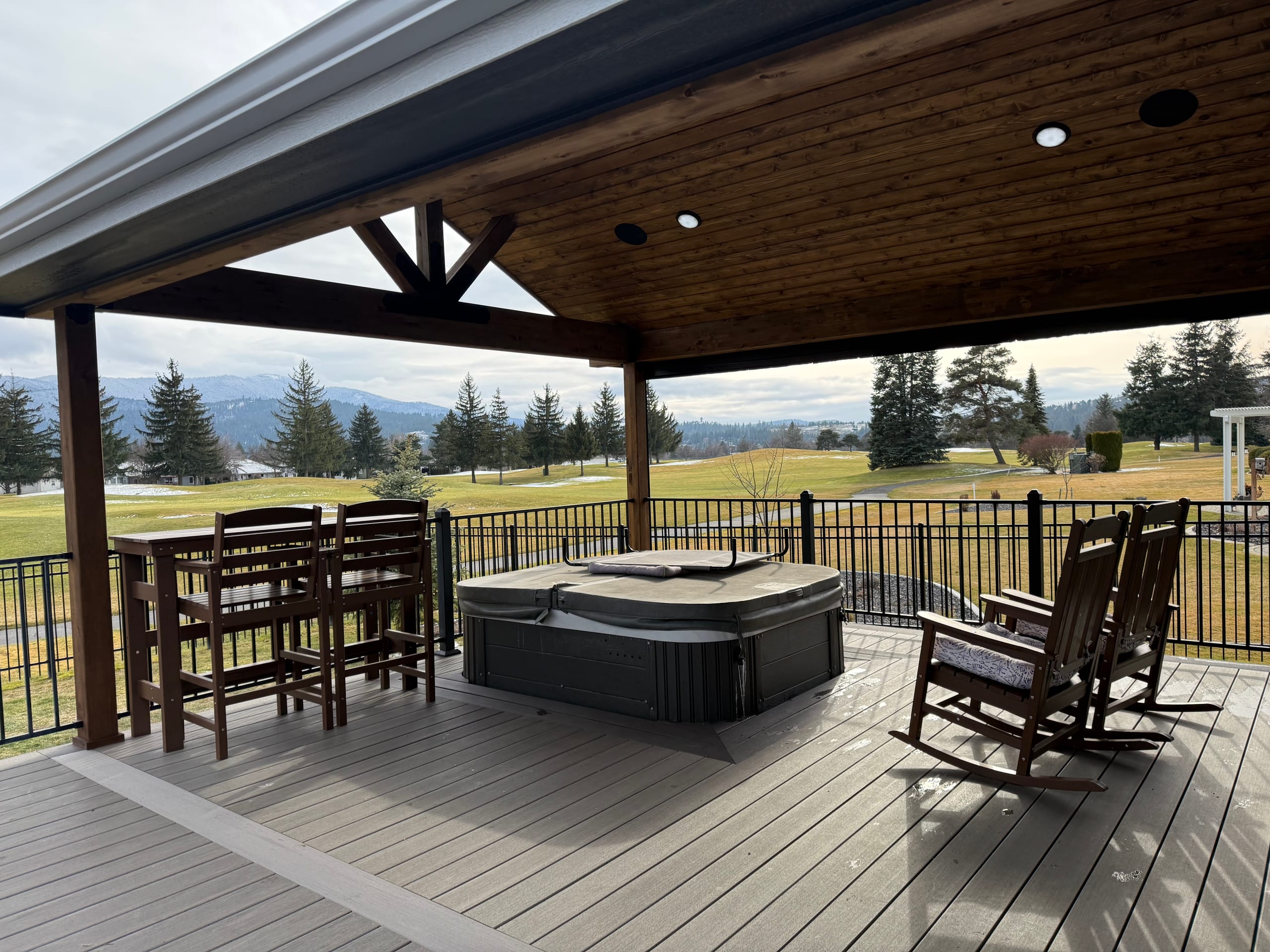 Covered deck under gabled timber roof with recessed lights, hot tub