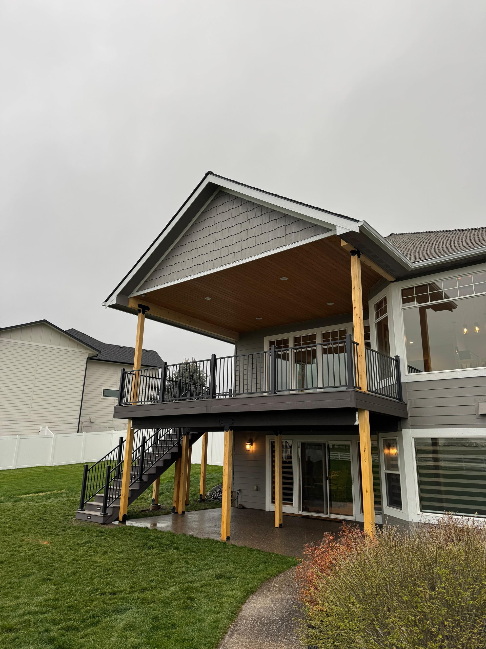 Covered second-story deck with a wood ceiling, wood posts and black railing