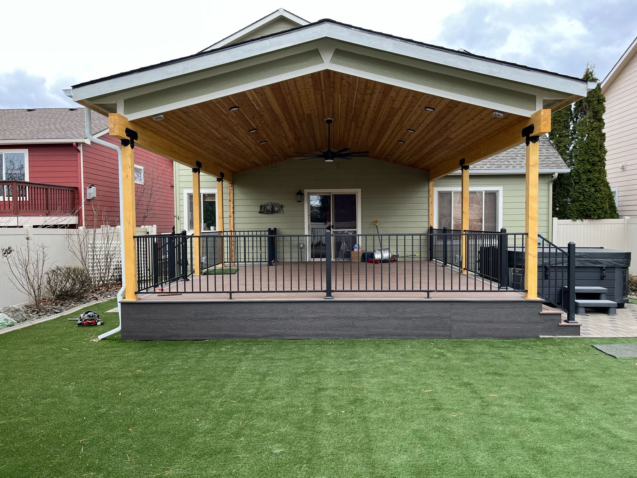 Gabled covered deck with stained cedar ceiling, cedar posts, dark composite decking