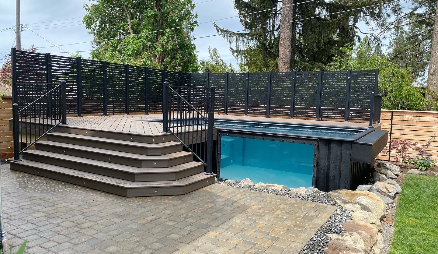 Glass-front raised pool with corner stairs, louvered screen and paver patio