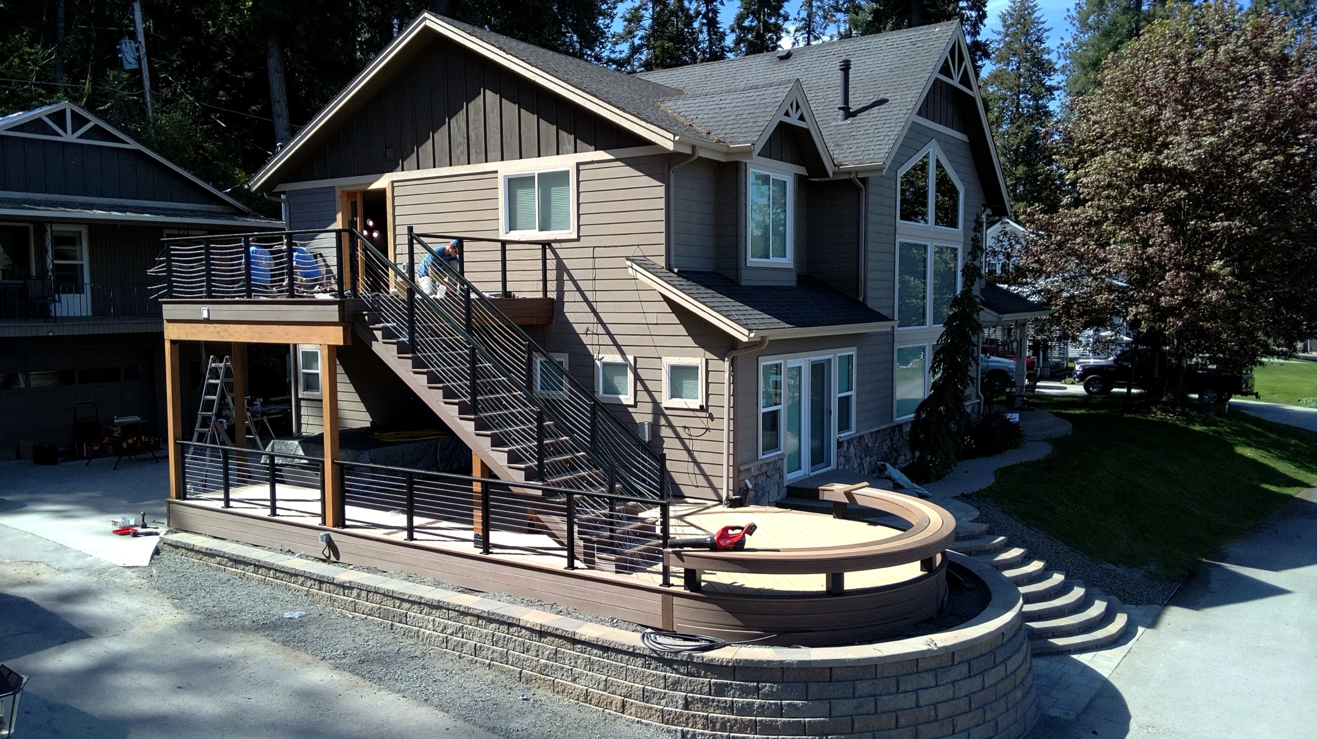 Lakefront house with cable-style black railing elevated deck, stairs and curved bench deck over stone block retaining wall