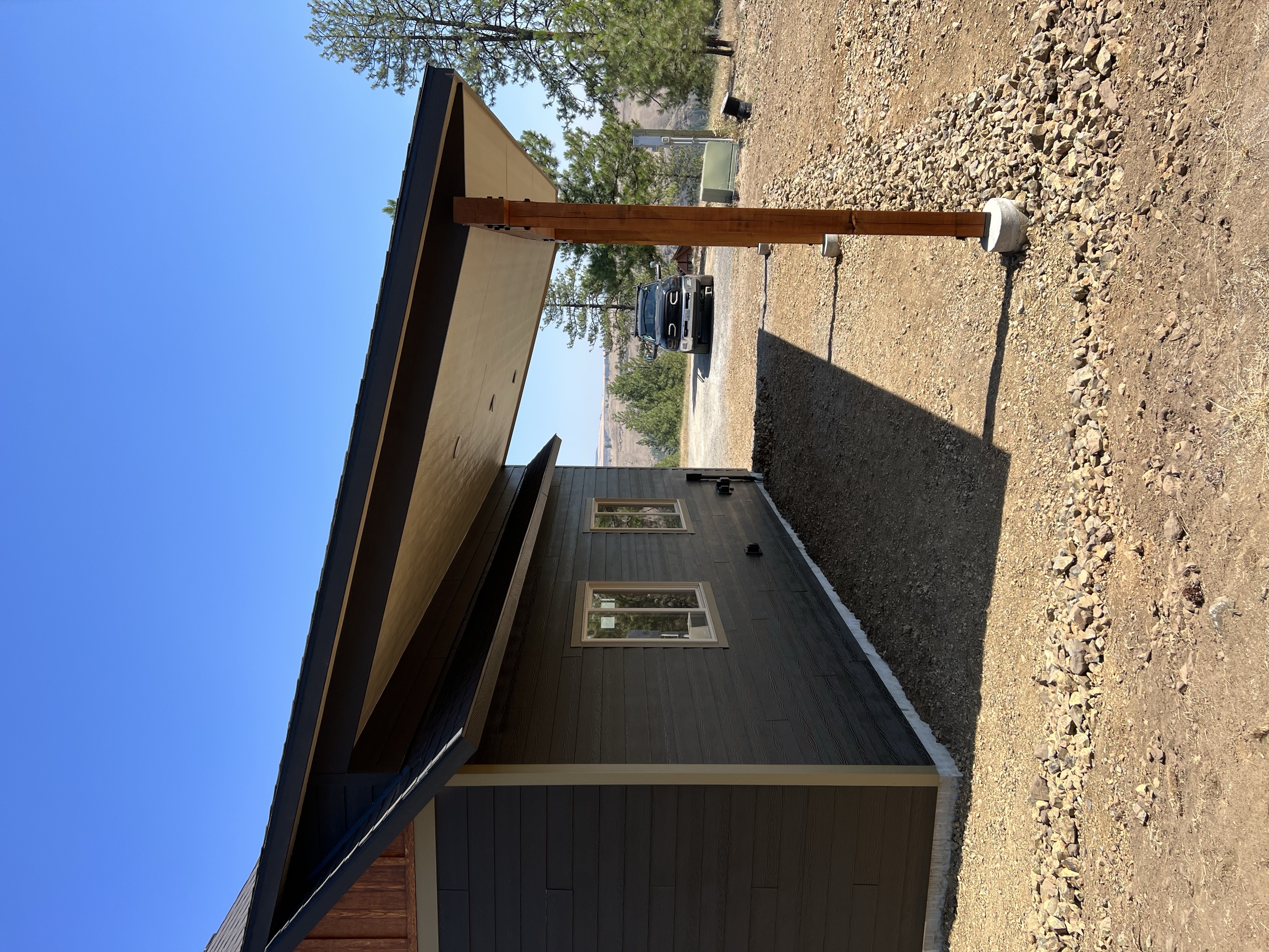 Lean-to roof on a timber post along the side of a dark-sided garage