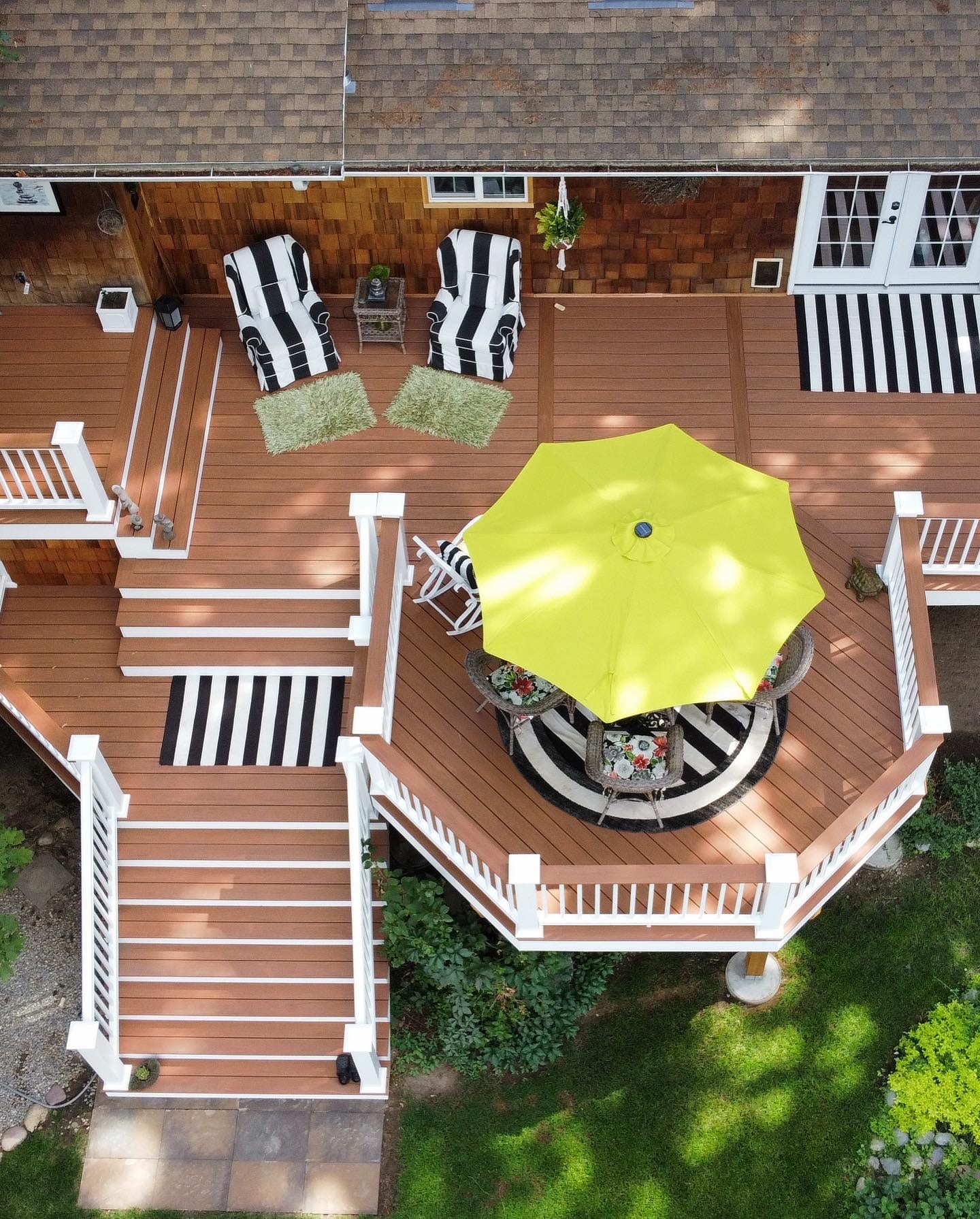Overhead view of a multi-level deck with white railing, stairs and patio umbrella