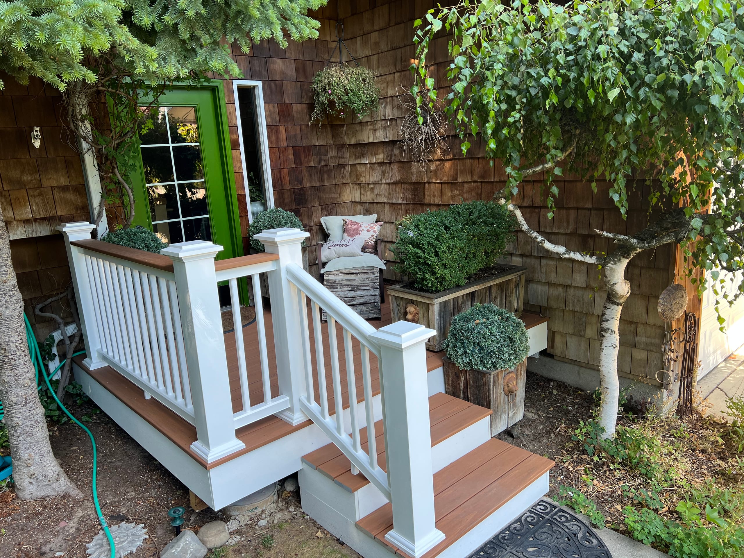 Small entry deck and stairs with white railing and brown decking at a green door