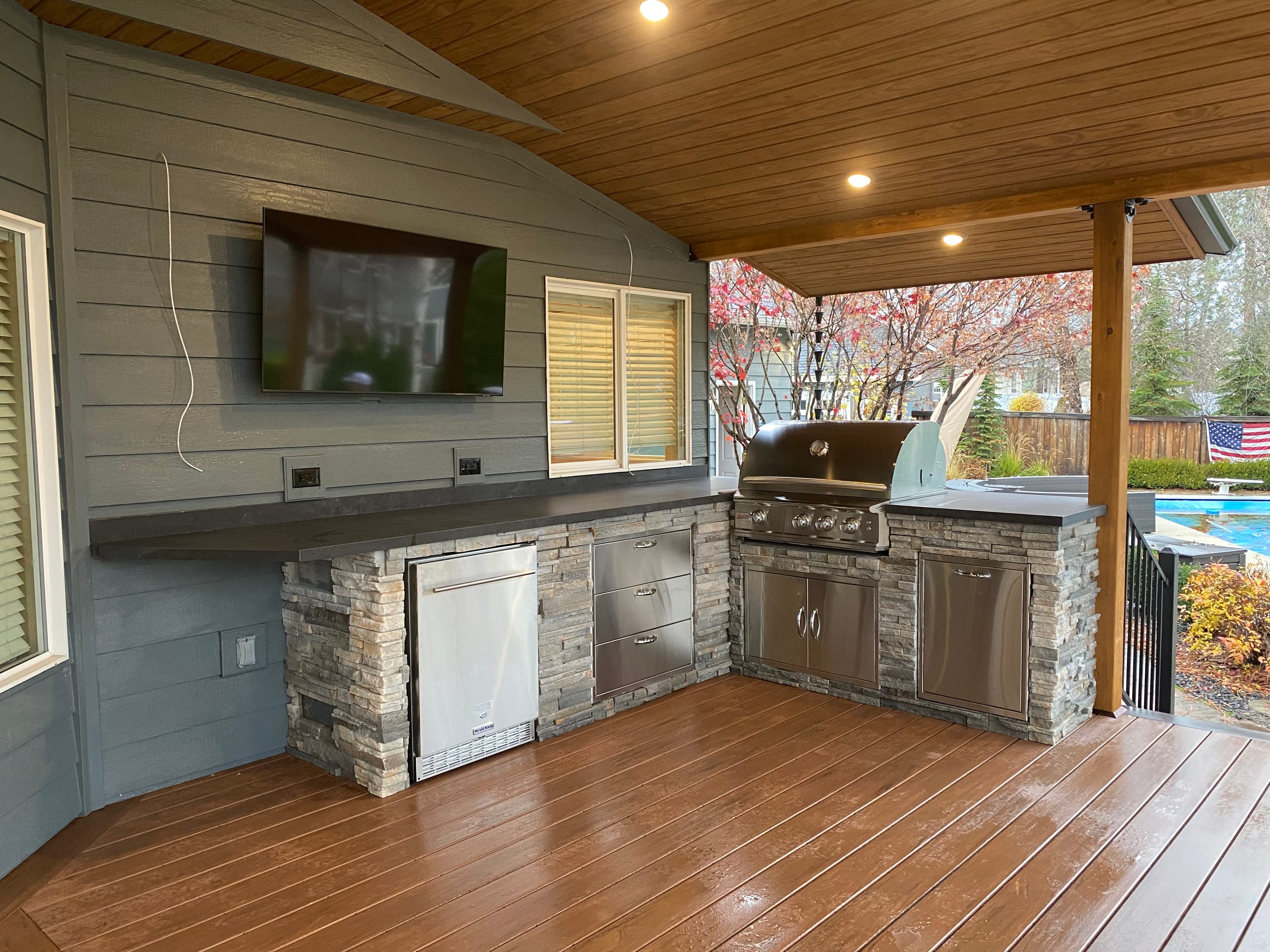 Stone-veneer outdoor kitchen with stainless grill and cabinets