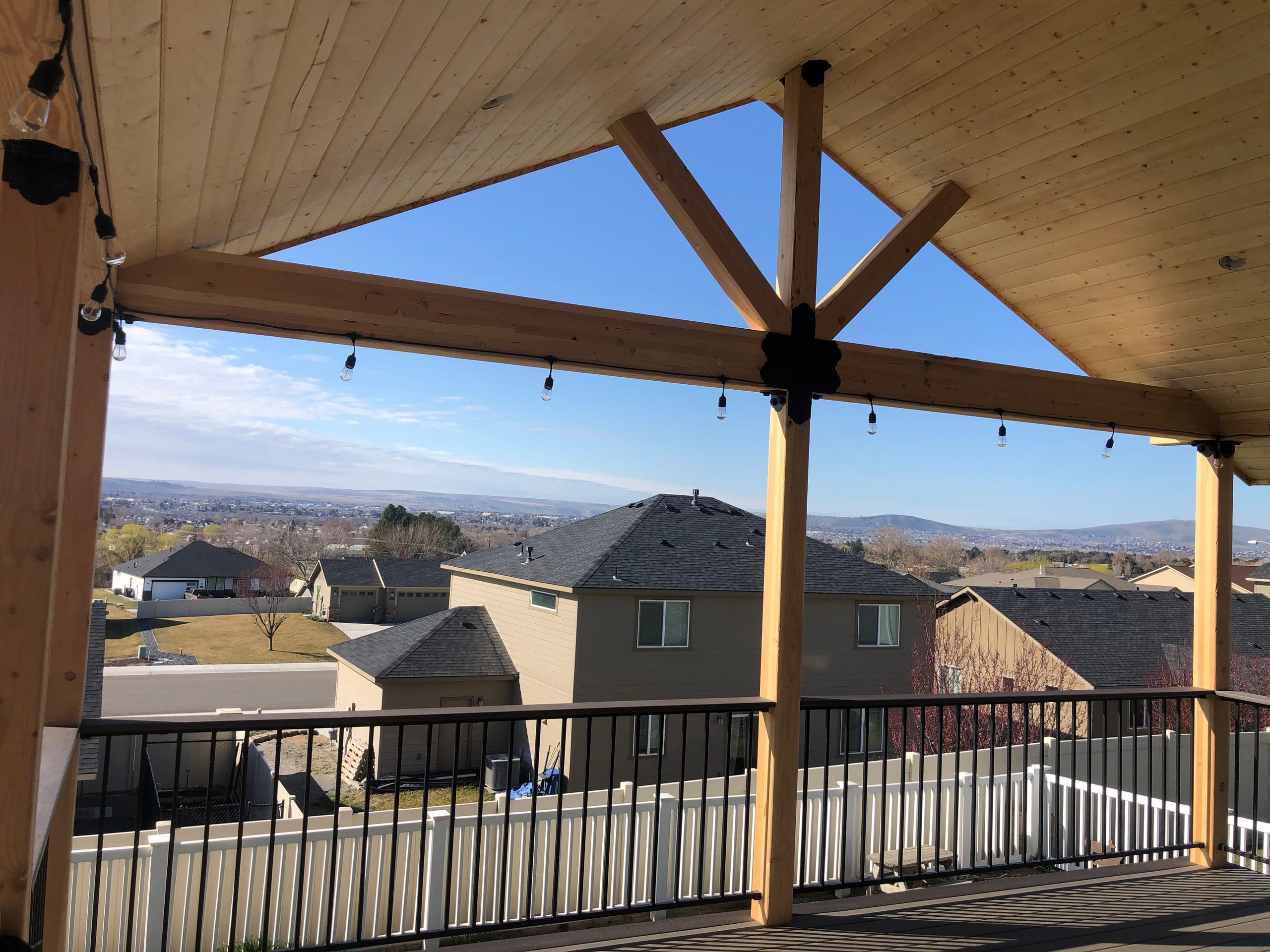 View from under a tongue-and-groove gable cover with timber king-post truss, string lights