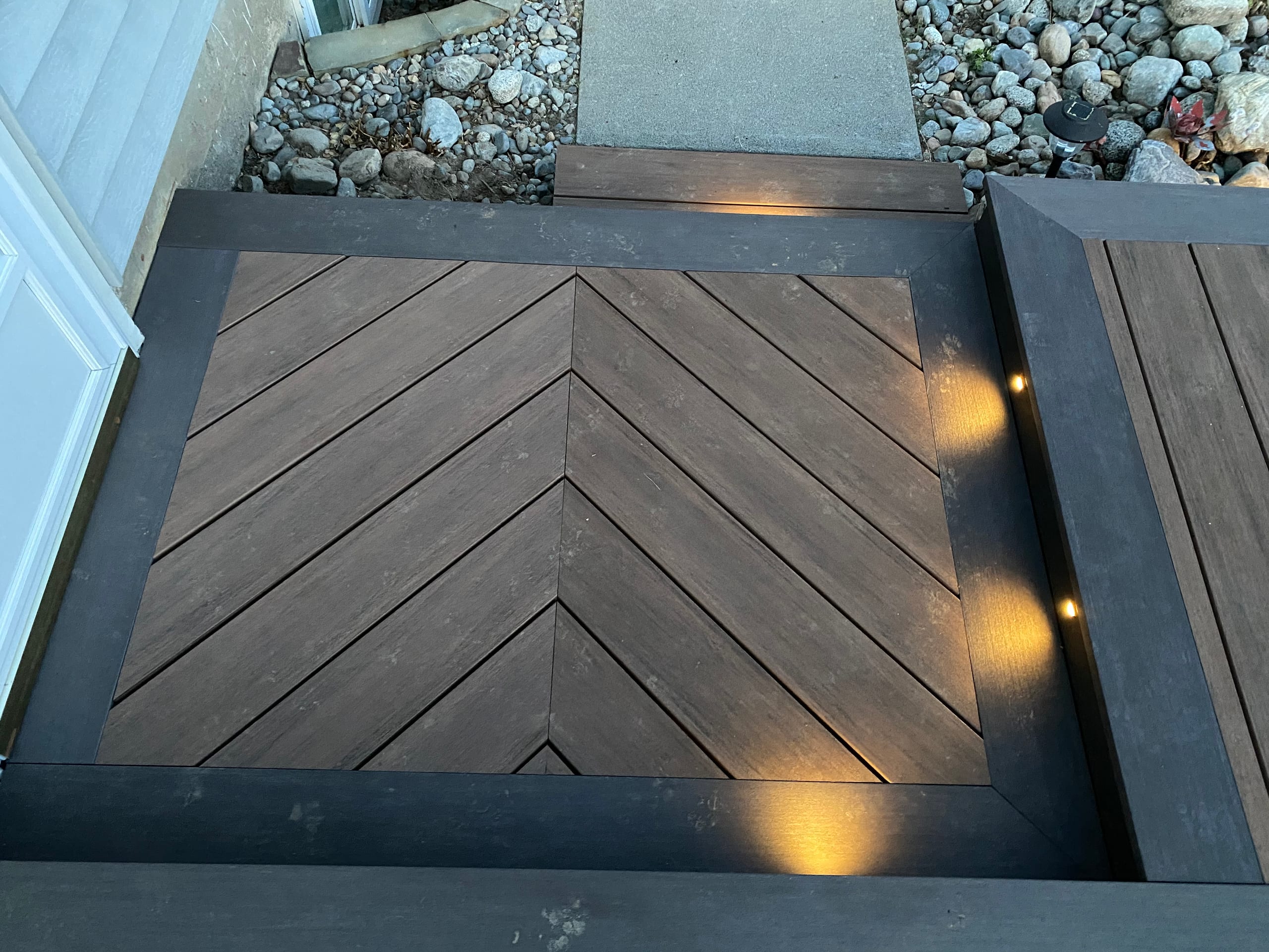 Top-down detail of dark composite herringbone inlay panel with darker border and recessed amber lights