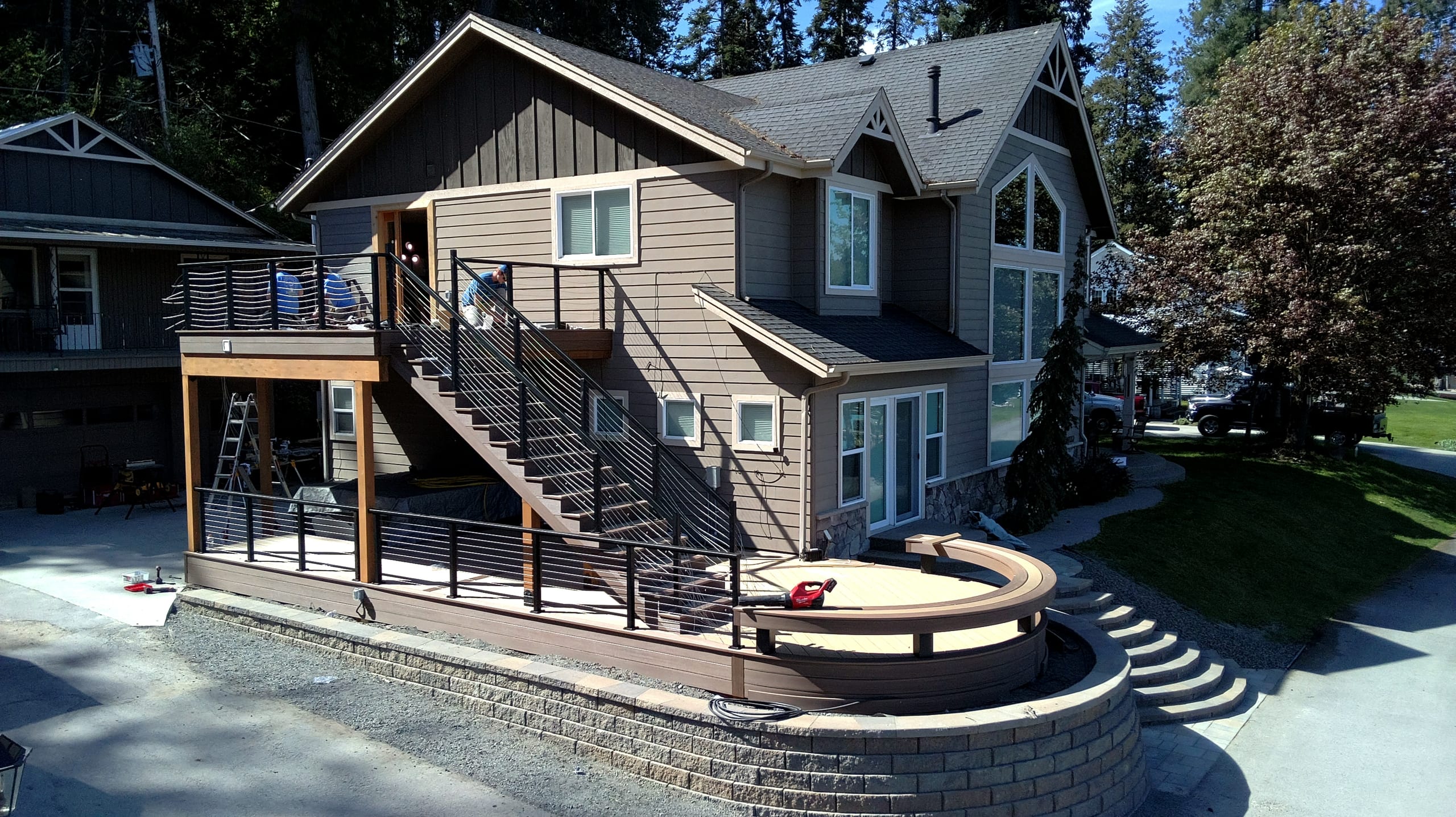Two-level deck with cable railing, stairs and a curved lower deck on a block retaining wall