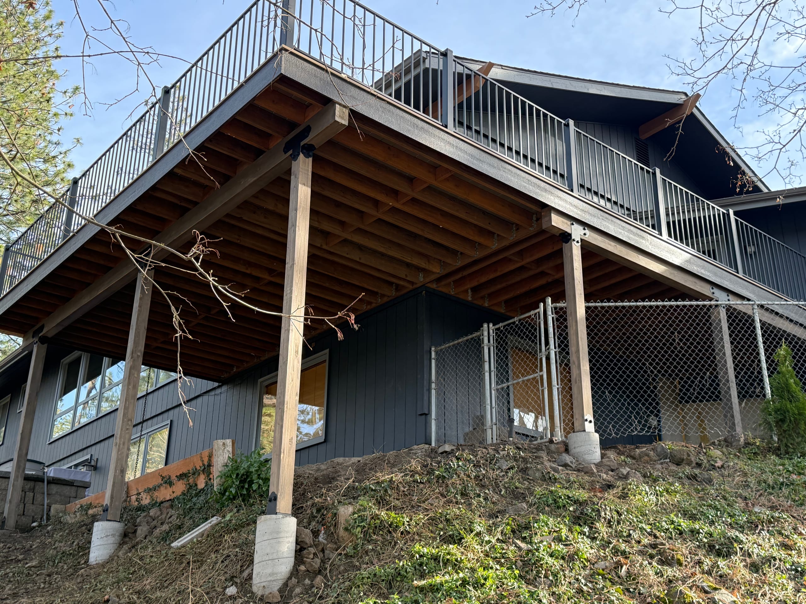 Underside of large elevated deck with joists, wood posts on concrete piers