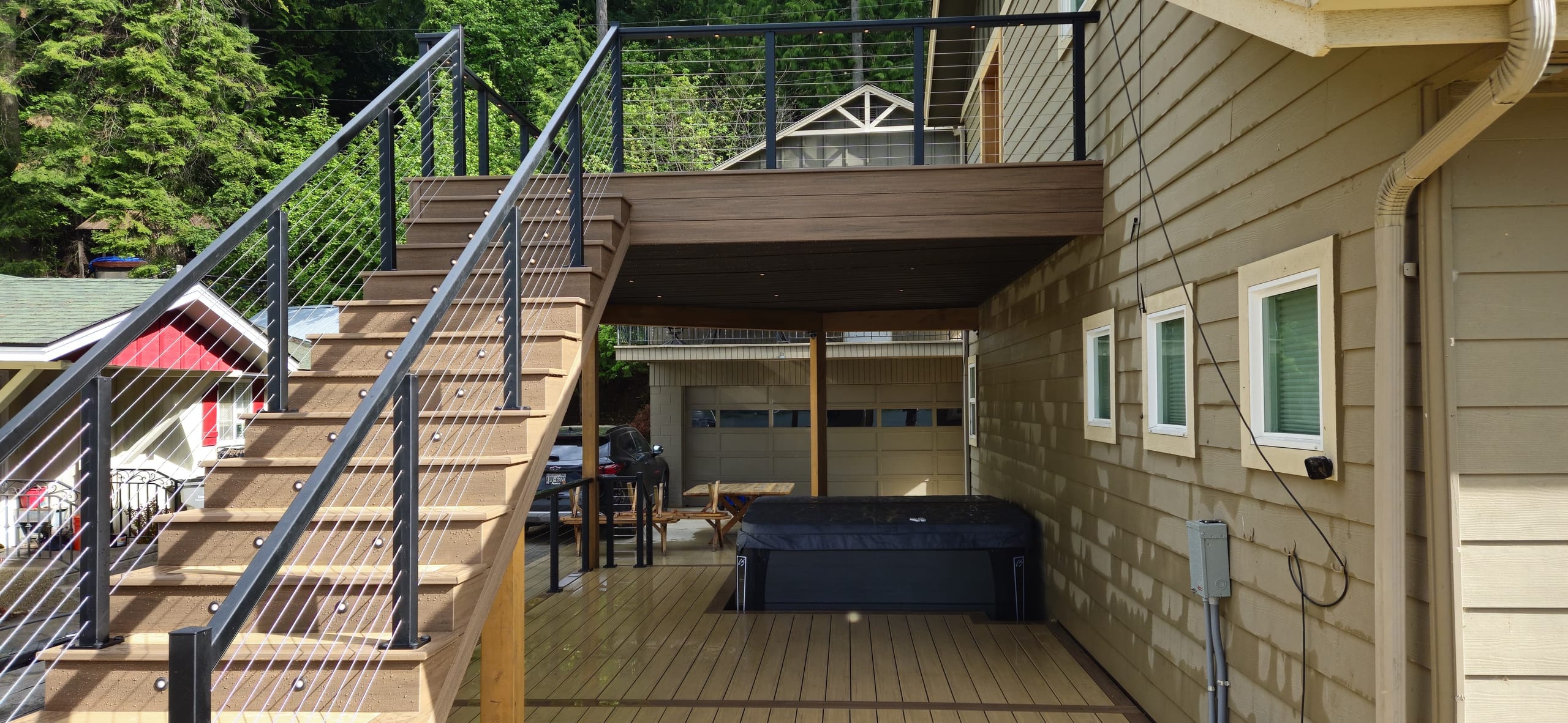 Wide deck stairs with cable railing leading to an upper deck above a hot tub
